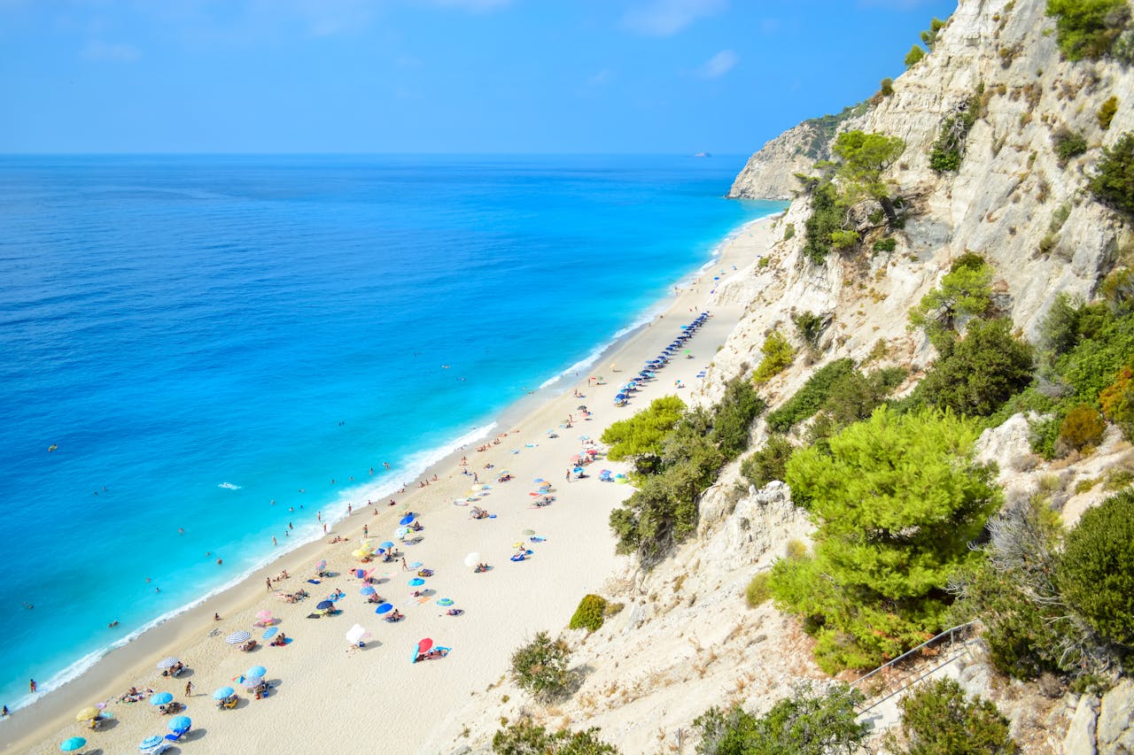 A breathtaking view of Egremni Beach in Greece with turquoise waters and vibrant umbrellas.
